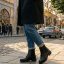 یک خانم ایستاده که بوت مشکی بندی پوشیده است