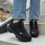 نمای نزدیک از کفش کتانی زنانه مشکی آدیداس (Adidas) پوشیده شده با شلوار جین روی پله‌ها.